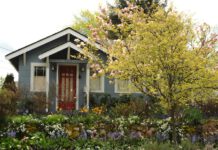 Najpiękniejsze domy z ogrodem. Jak zaaranżować przestrzeń wokół domu? Drewniany, niebieski domek z bujnym ogrodem